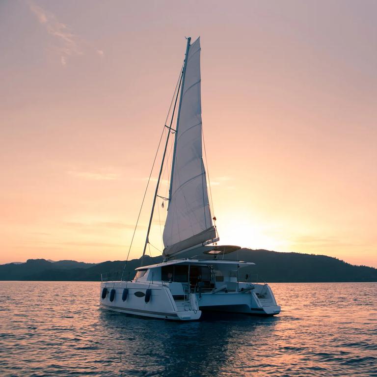 Yacht - Catamaran in the ocean. Sailing at sunset