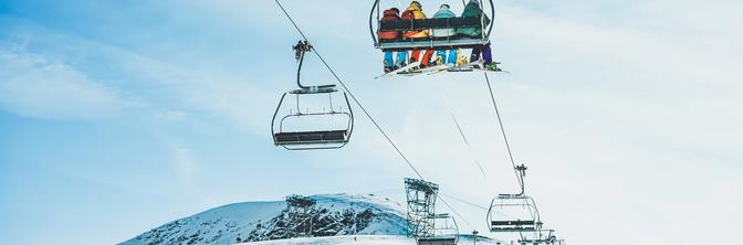 People on ski lift in winter ski resort - Holidays, snow gear renting, skiing, snowboarding and mountain landscape concept - Focus on guys sitting in cable car